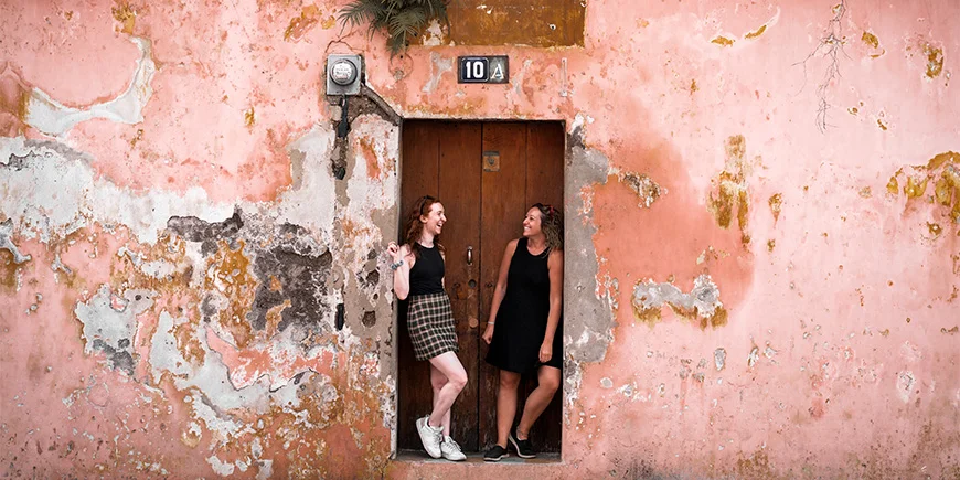 To kvinder står foran farverig mur i Antigua i Guatemala