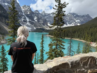 Kvinde i TourCompass-t-shirt kigger ud over vandet ved Lake Louise i Canada