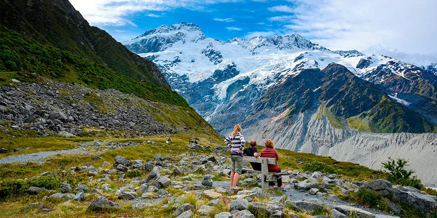 Famlie på tre kigger på bjerge fra udsigtspunktet Kea Point i Mount Cook Nationalpark