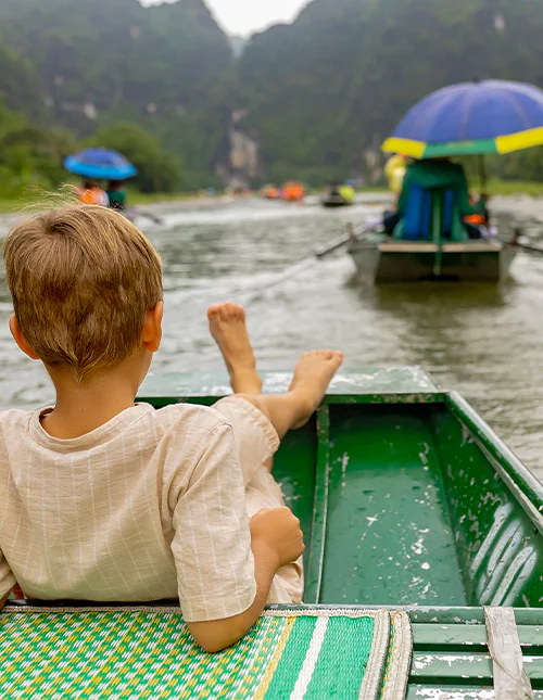 Et barn nyder en bådtur i Ninh Binh, Vietnam