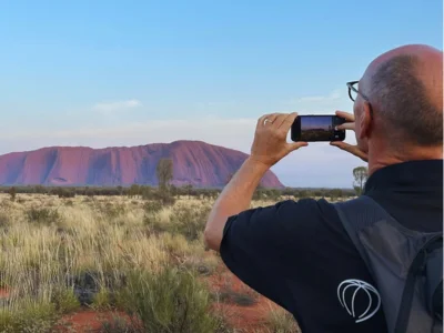 Mand tager billede med mobiltelefon af Uluru i Australien