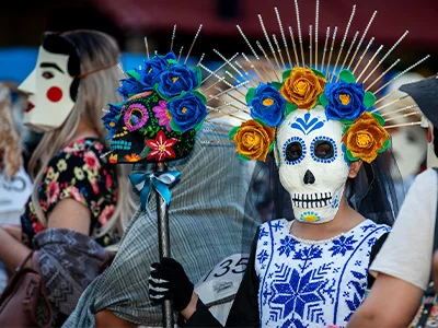 Kvinde klædt ud med skelet-ansigt og blomster i håret i forbindelse med de dødes dag i Mexico