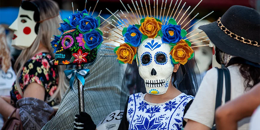 Kvinde klædt ud med skelet-ansigt og blomster i håret i forbindelse med de dødes dag i Mexico
