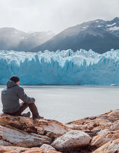 Mand sidder foran Perito Moreno-gletsjeren i Los Glaciares Nationalpark
