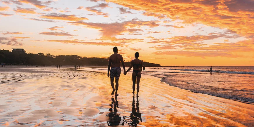 Mand og kvinde går på Tamarindo Beach i Costa Rica