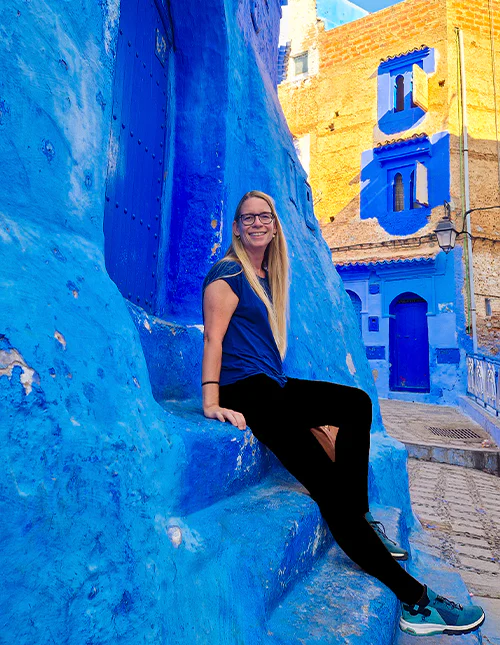 Kvinde sidder på trappe i den blå by Chefchaouen i Marokko 
