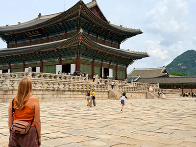 Kvinde står og kigger på Gyeongbokgung-paladset i Seoul