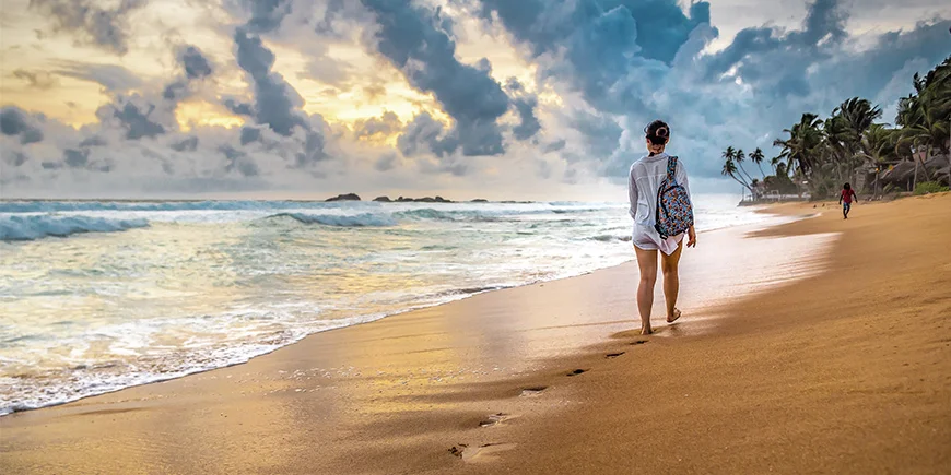 Kvinde går på stranden i Sri Lanka