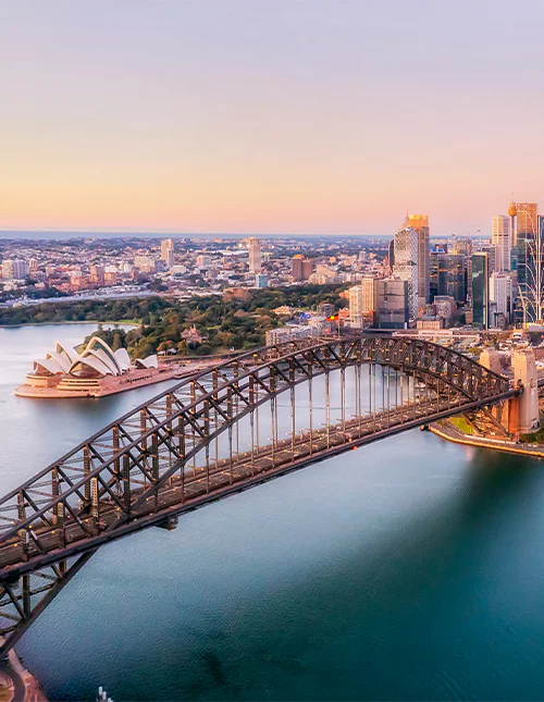Luftfoto af Sydney Harbour Bridge badet i et lilla skær.