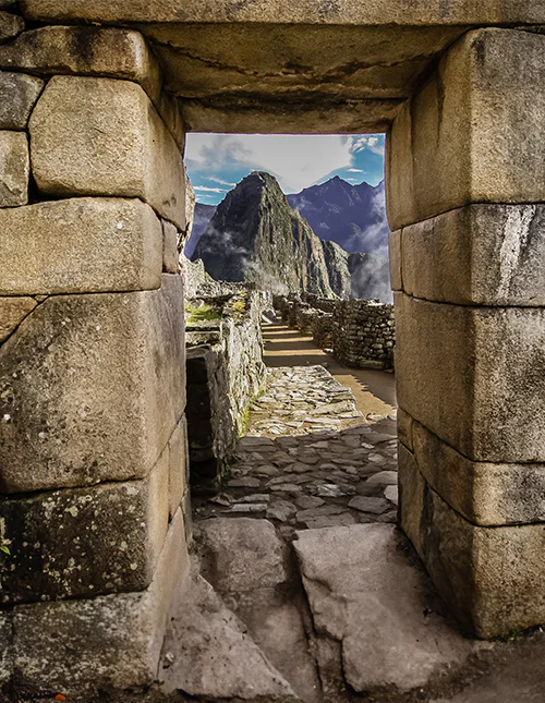 Stenport med udsigt til Machu Picchu og tågede Andesbjerge.