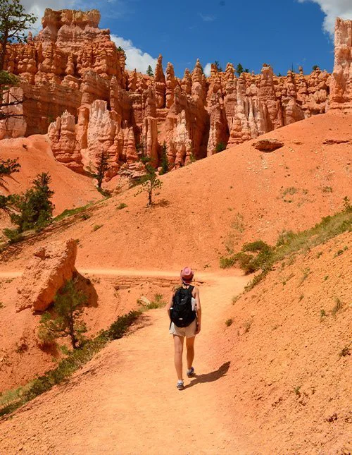 Person går på sti mellem de ikoniske orange klipper i Bryce Canyon National Park i Utah, USA.