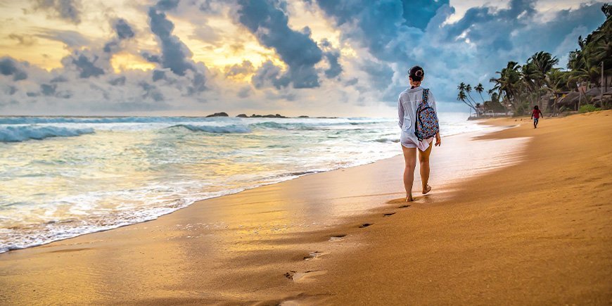 Kvinde går på en strand i Sri Lanka