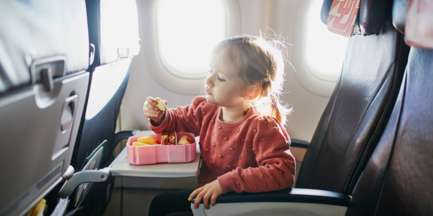 Barn spiser snacks på sædet i fly