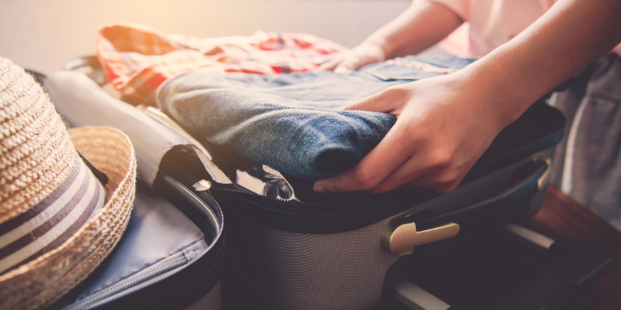 Kvinde pakker tøj til sin rejse i sit soveværelse
