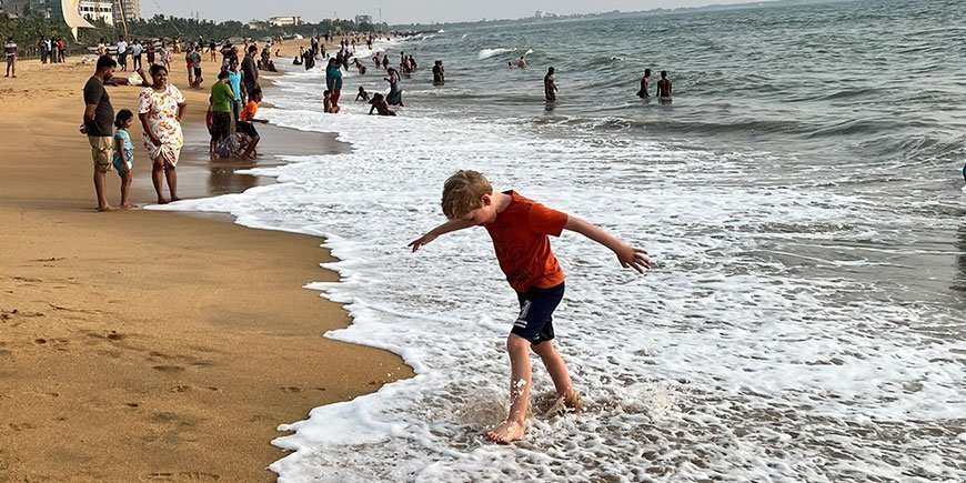Dreng går i vandkanten på gylden strand i Sri Lanka