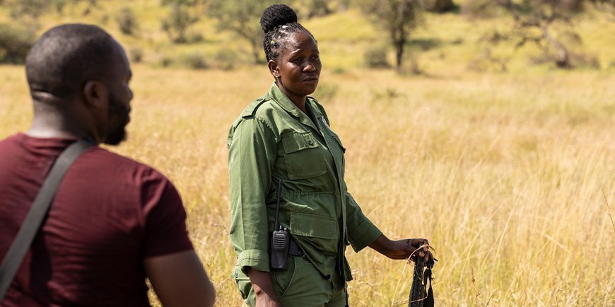 Kvinde sår med riffel på savannen