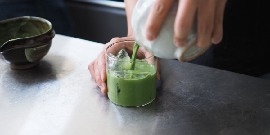 Person hælder matcha-te op i glas