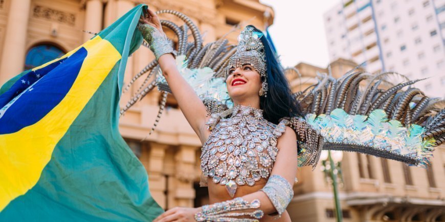 Brasiliansk kvinde iklædt farverigt kostume holder brasiliansk flag