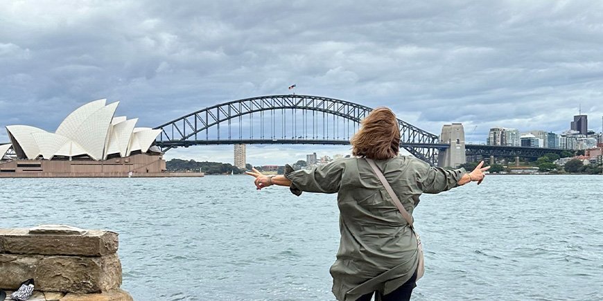 Beate står foran Operahuset og Sydney Harbour Bridge i Australien