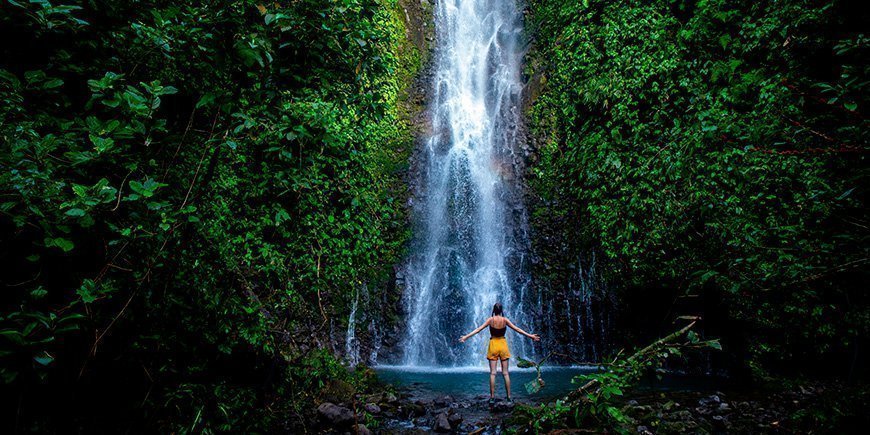 Kvinde står foran vandfald i Costa Rica