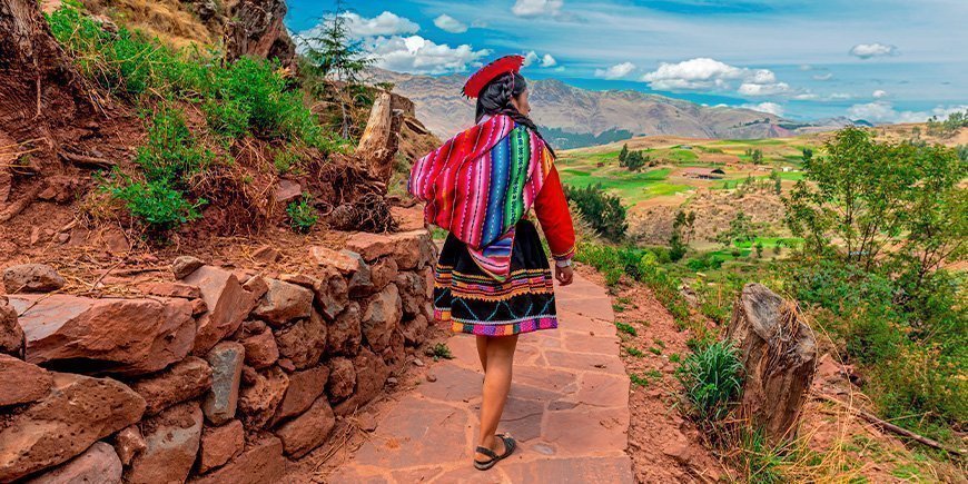 Indfødt kvinde går langs en inkamur i Cusco i oktober måned