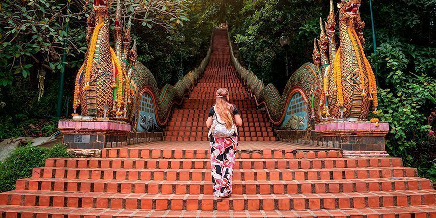 Kvinde går op trapperne ved Doi Suthep-templet i Chiang Mai i Thailand.