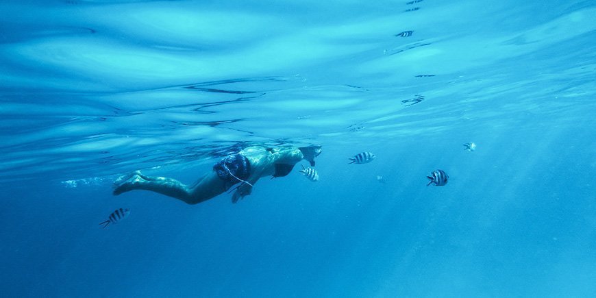 Kvinde snorkler under vandet på Zanzibar