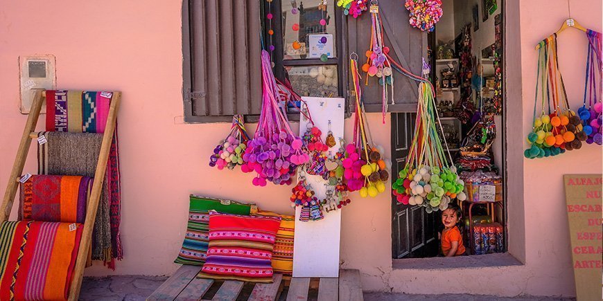 lille, lokal butik i Purmamarca i Argentina og en pige, der sidder i døråbningen.