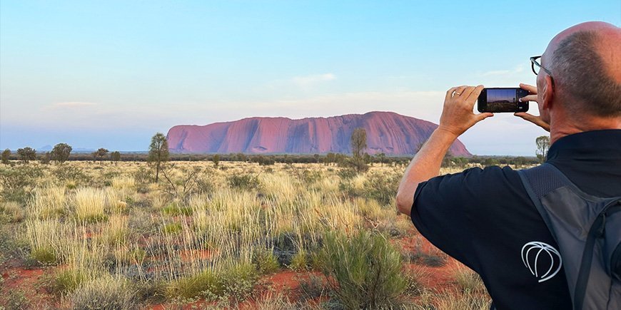 Mand tager billede med mobiltelefon af Uluru i Australien