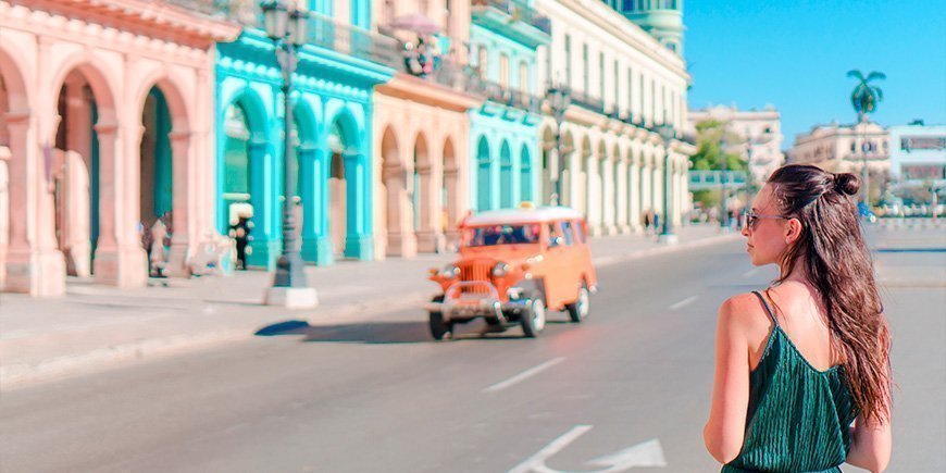 Kvinde går på gade med farverige bygninger i Havana i Cuba 