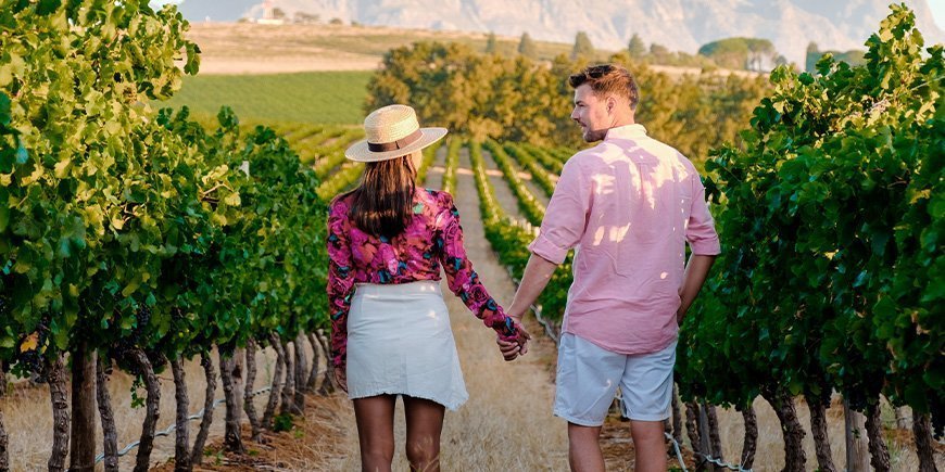 Kvinde og mand holder i hånd på vinmark i Sydafrika