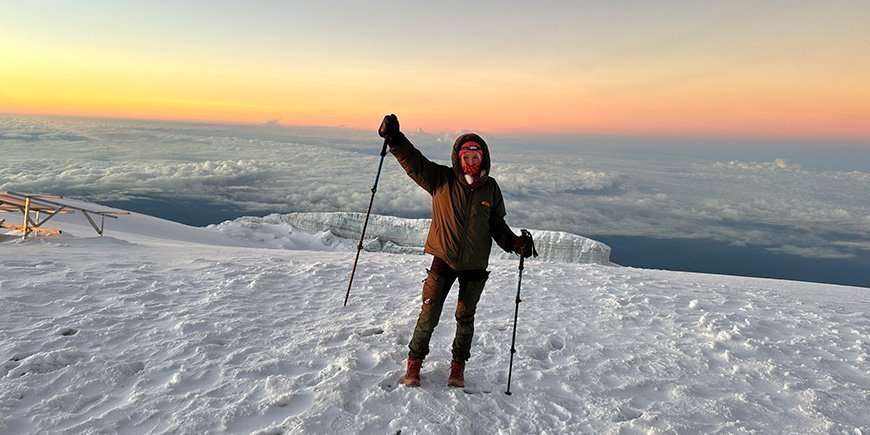 Kvinde står i sneen på toppen af Kilimanjaro.
