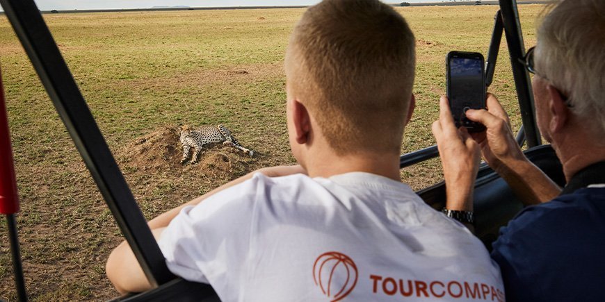 To mænd kigger på gepard, der ligger på savannen på Serengeti
