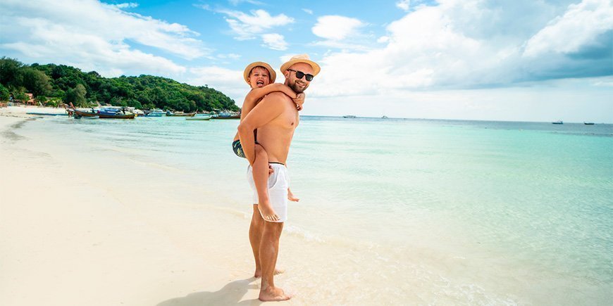 Far og søn på en strand i Thailand