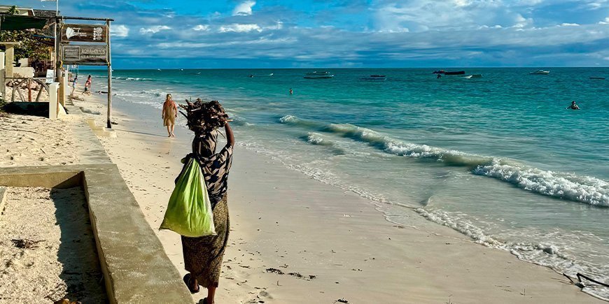 Lokal kvinde går på stranden i Paje