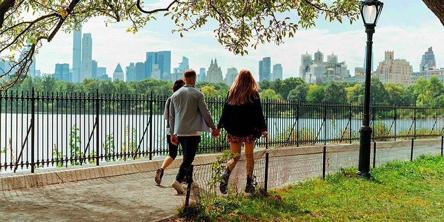 Par går hånd i hånd i solskinsvejr i Central Park, New York City