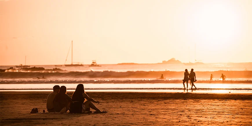 Folk nyder solnedgangen på Tamarindo-stranden i Costa Rica