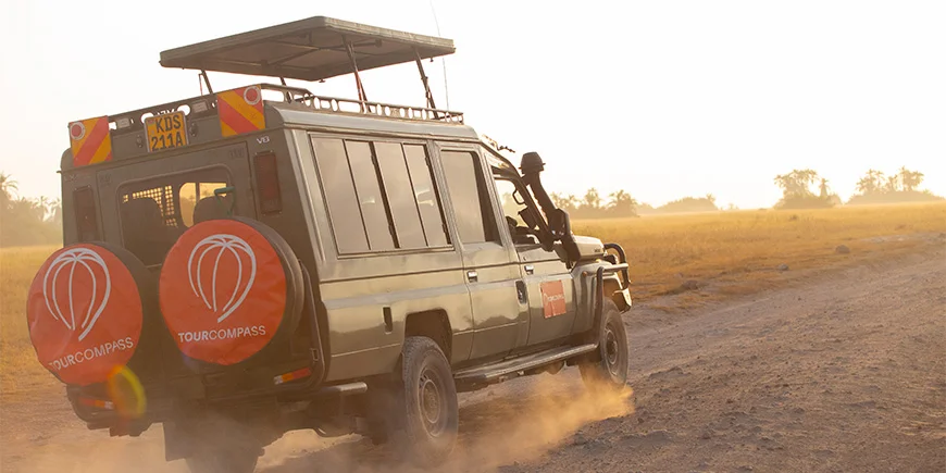 Jeep med TourCompass-logo kører på savannen i Kenya