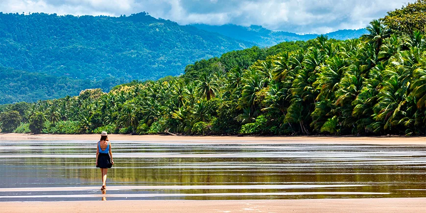 Kvinde går tur ved vandet på Manuel Antonio strand i Costa Rica