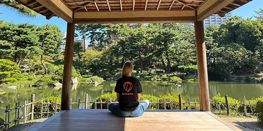Kvinde i TourCompass-tshirt i smuk japansk have i Hiroshima