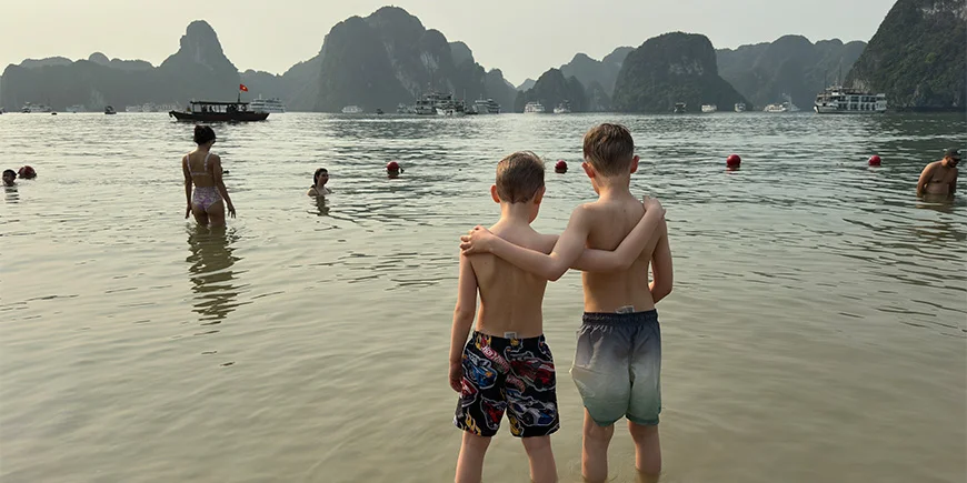 To drenge holder om hinanden på en strand i Halong-bugten