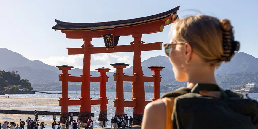 Kvinde kigger på den røde helligdom på Miyajima Island i Hiroshima